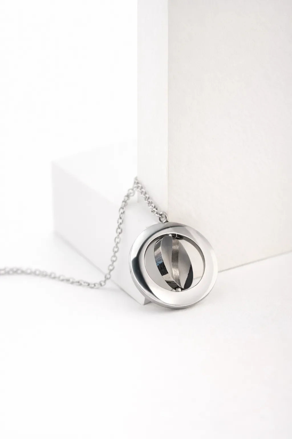 Silver spinning pendant necklace on a white display