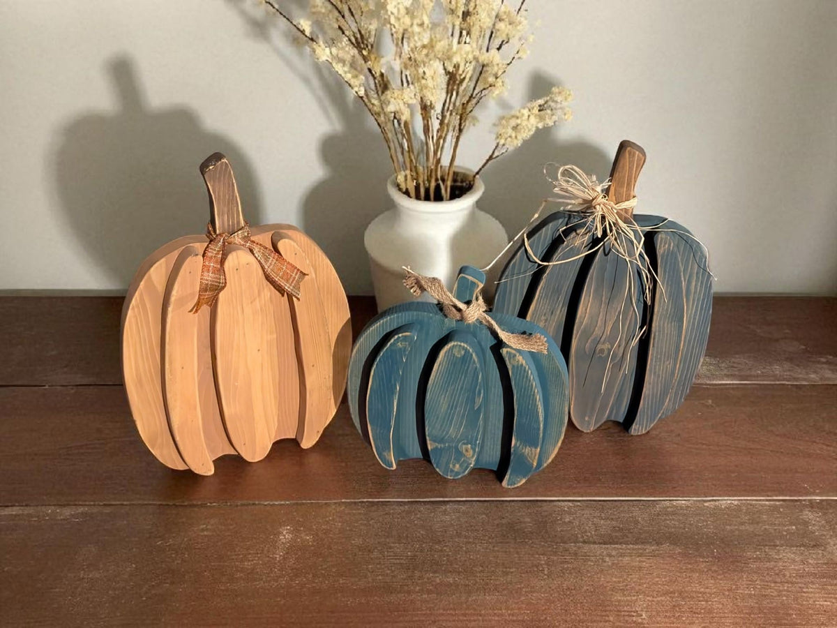 Handcrafted ribbed wood pumpkins in orange, blue, and cream with dried florals