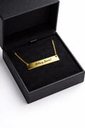 Gold bar necklace engraved in handwriting, shown in a gift box