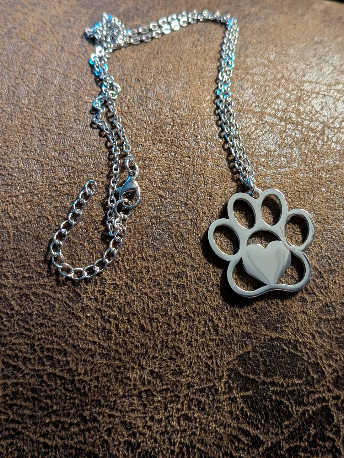 Silver dog paw necklace with engraved detail on leather