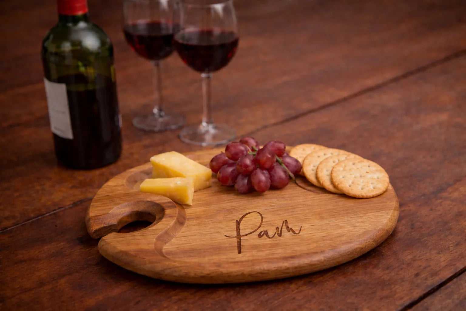 Round wood wine appetizer plate with cheese, grapes, and wine
